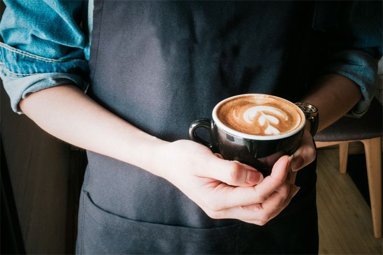 Cappuccino mit Latte Art in der Hand