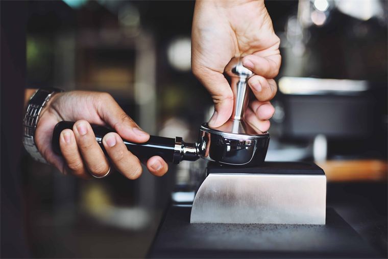 Barista beim Tampern des Kaffeemehls im Siebträger